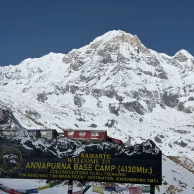 Welcome sign at Annapurna Base Camp (4,130 m) with snow-covered Mount Annapurna in the background, Nepal