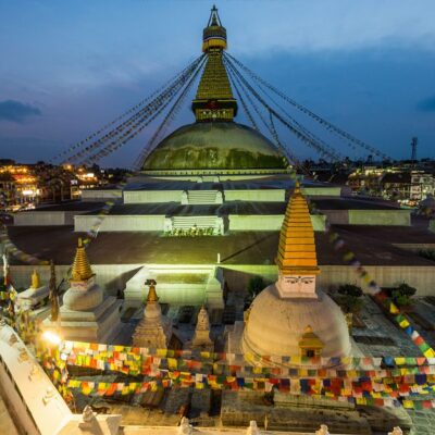 Boudhanath Stupa at dusk with colorful prayer flags in Kathmandu, Nepal.